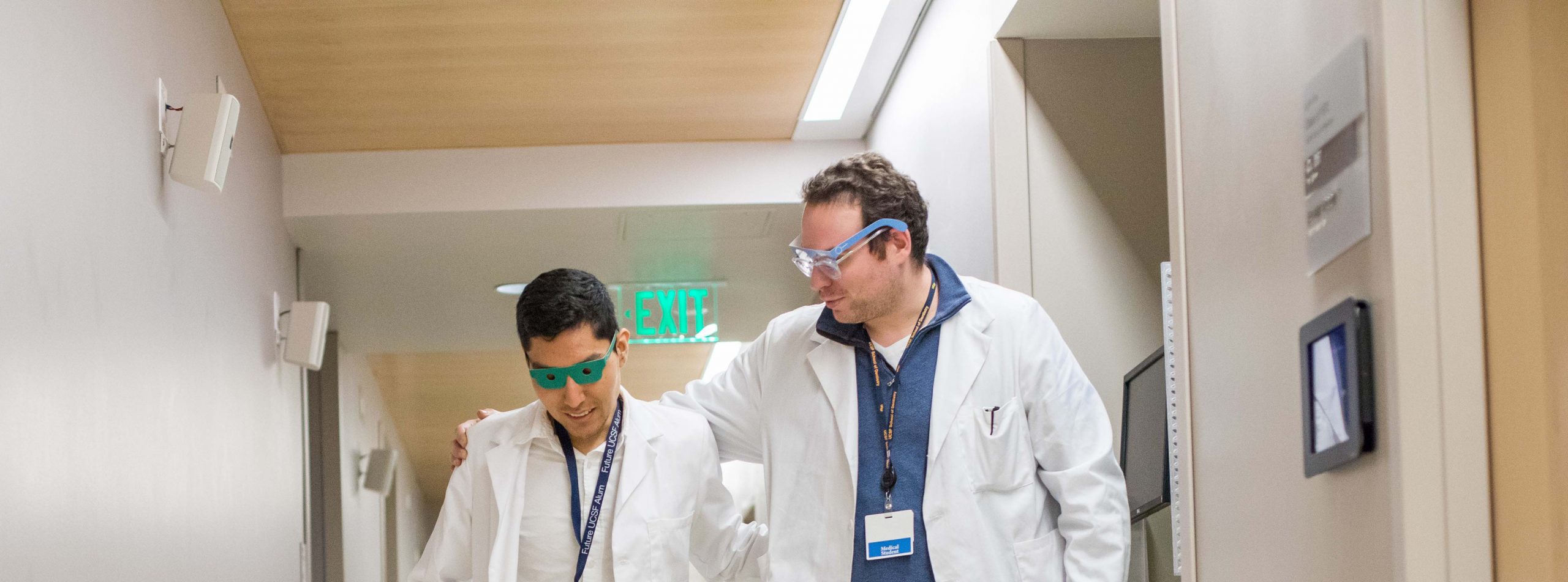 First-year medical student Alexander Tenorio (left) experiences a simulated patient ailment by wearing special glasses that replicate having glaucoma. Ross Linker (right) works to guide Tenorio while wearing glasses that replicate macular degeneration. The experience was part of geriatrics education at the Kanbar Center.
